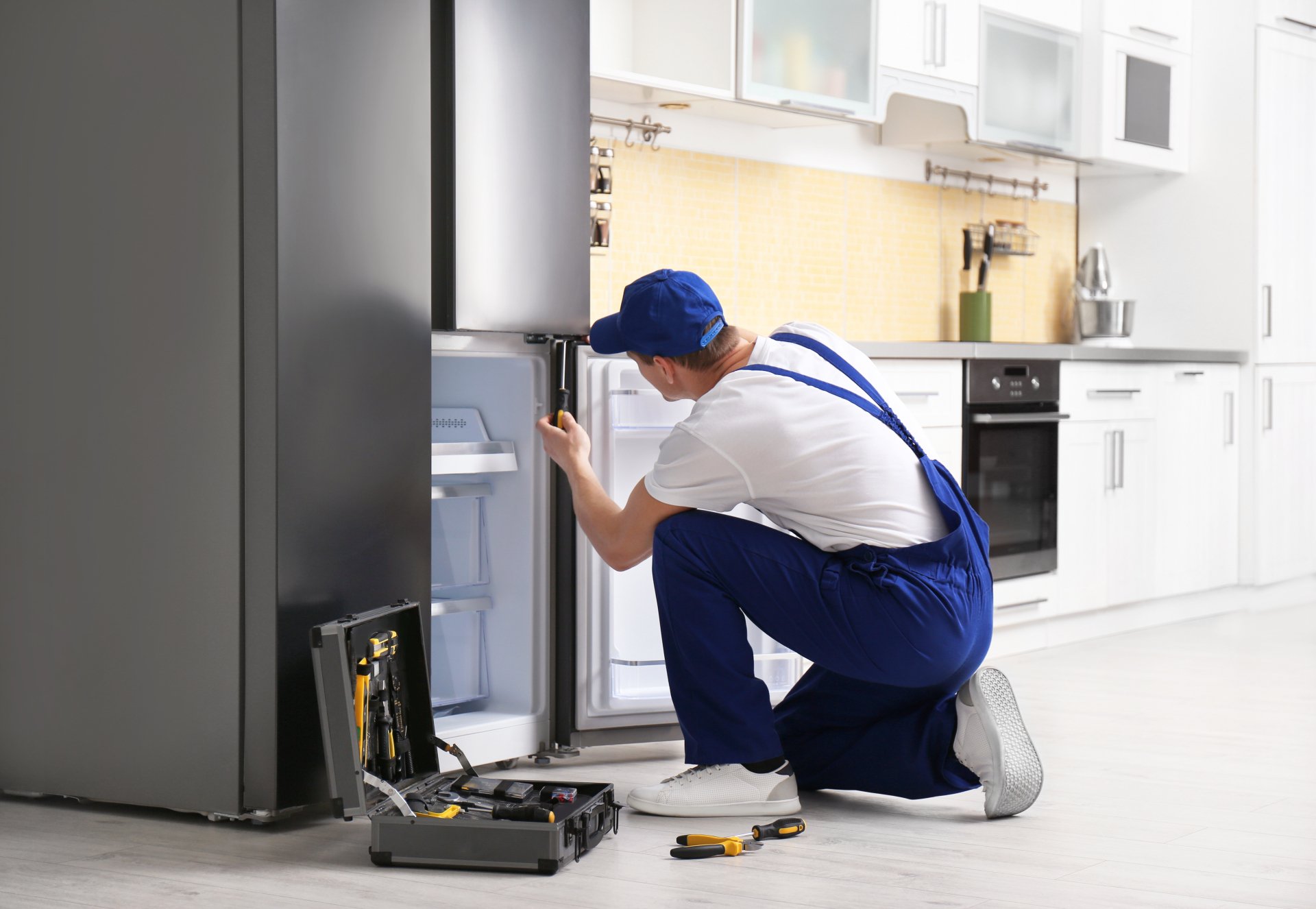 a technician repairing a refrigerator - Raleigh Appliance Repair Experts