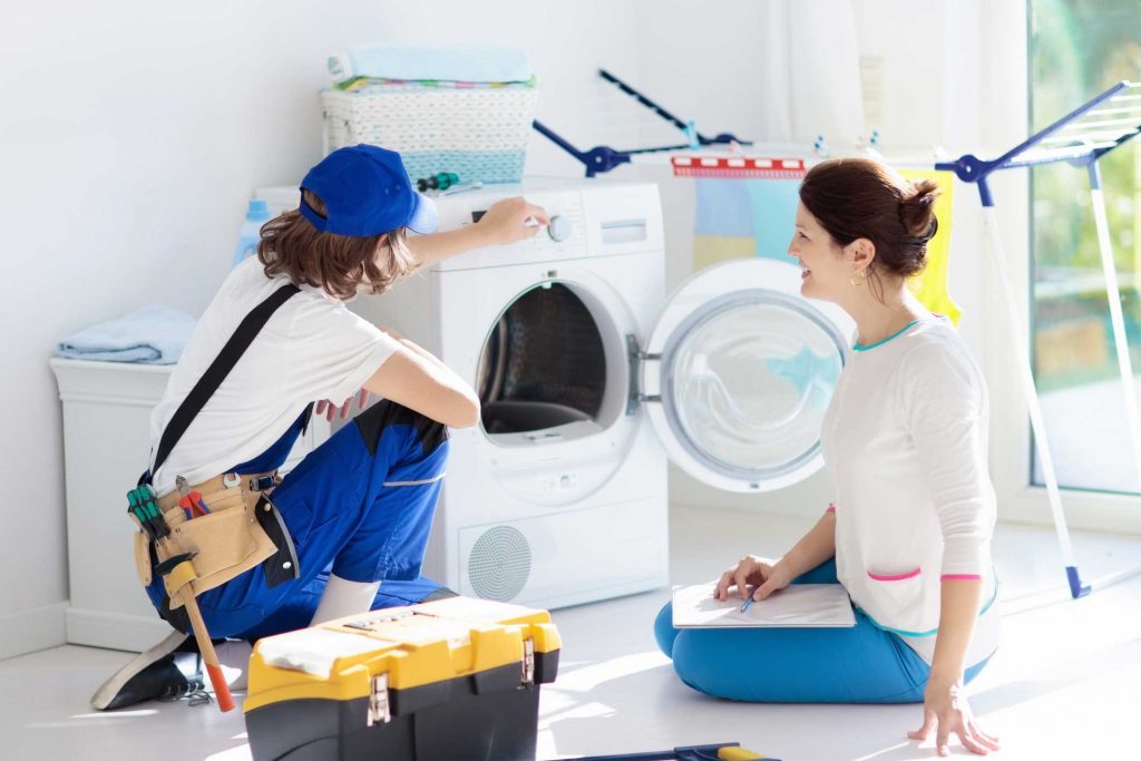 a technician repairing a washer while woman is watching - appliance repair service Raleigh