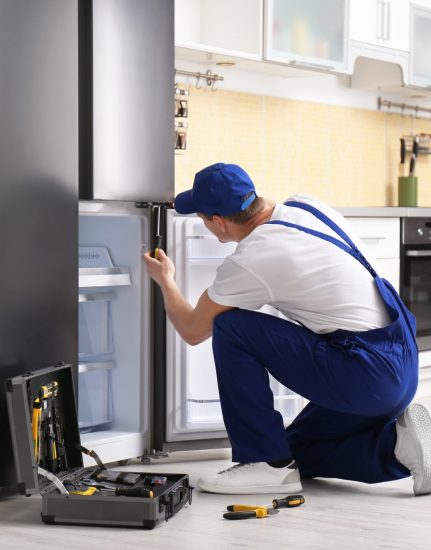 a technician repairing a refrigerator - Raleigh Appliance Repair Experts